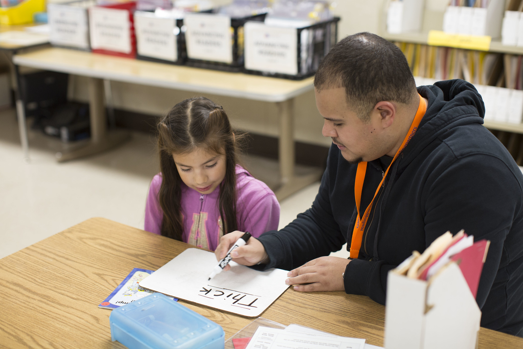 Student and tutor reading the word "thick" on a whiteboard, student using her brain to decode the word