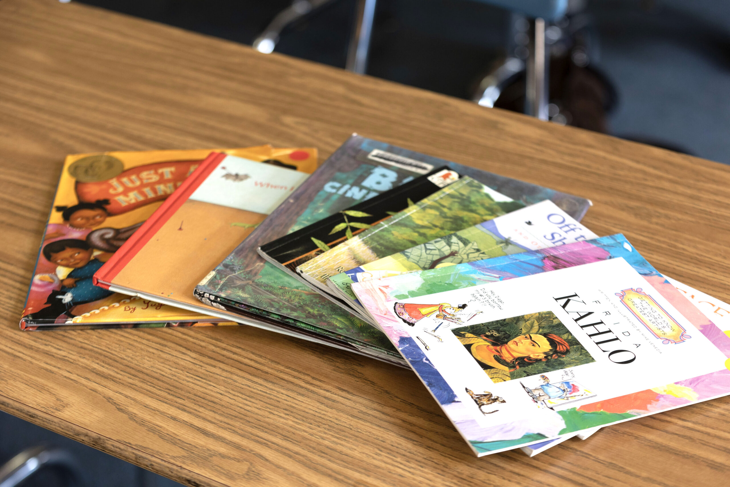 books about empowered women are spread out on a desk, the top book is about frida kahlo