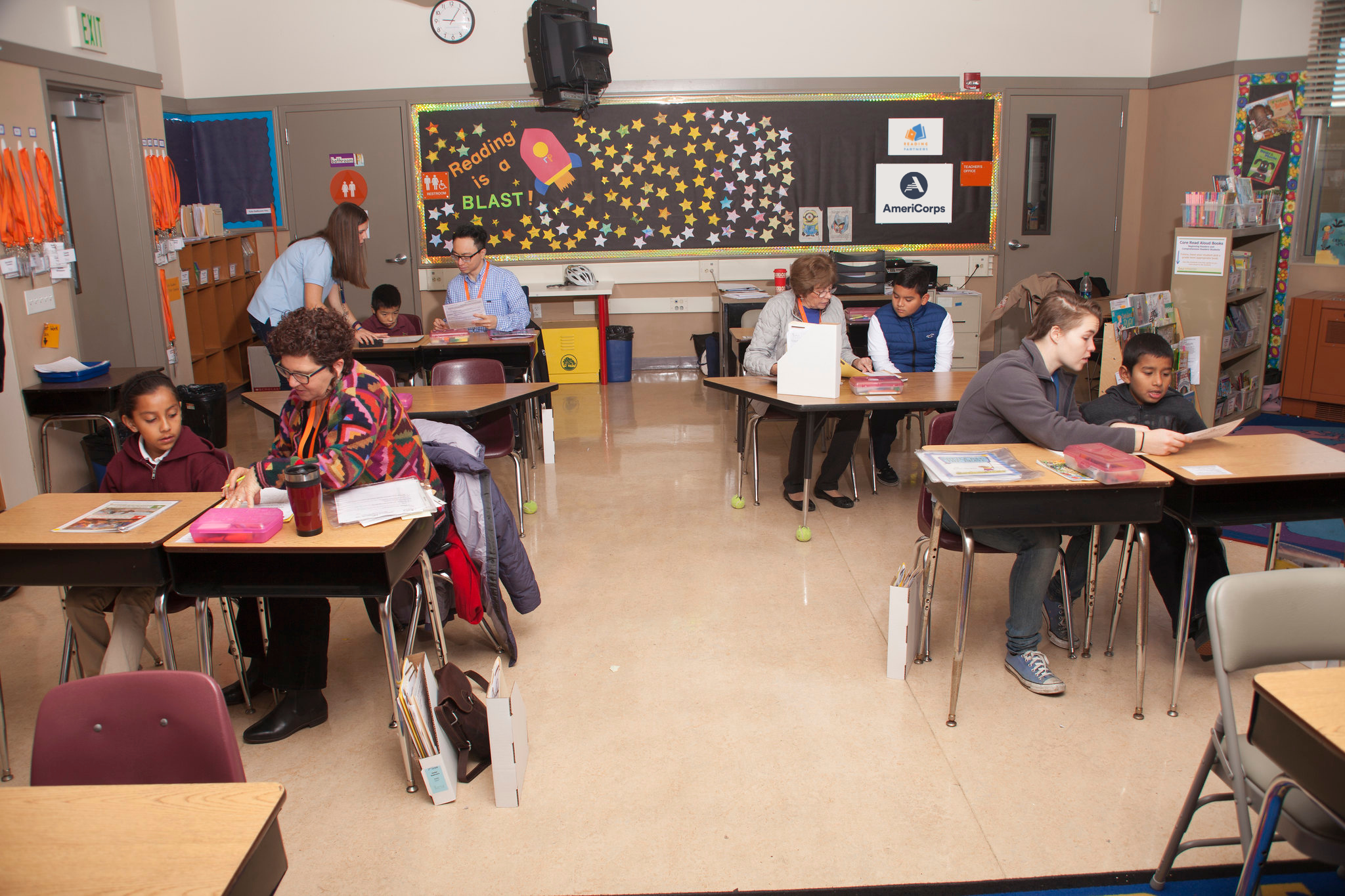 A Reading Partners reading center in which four tutor-student pairs are shown working together on literacy lessons.