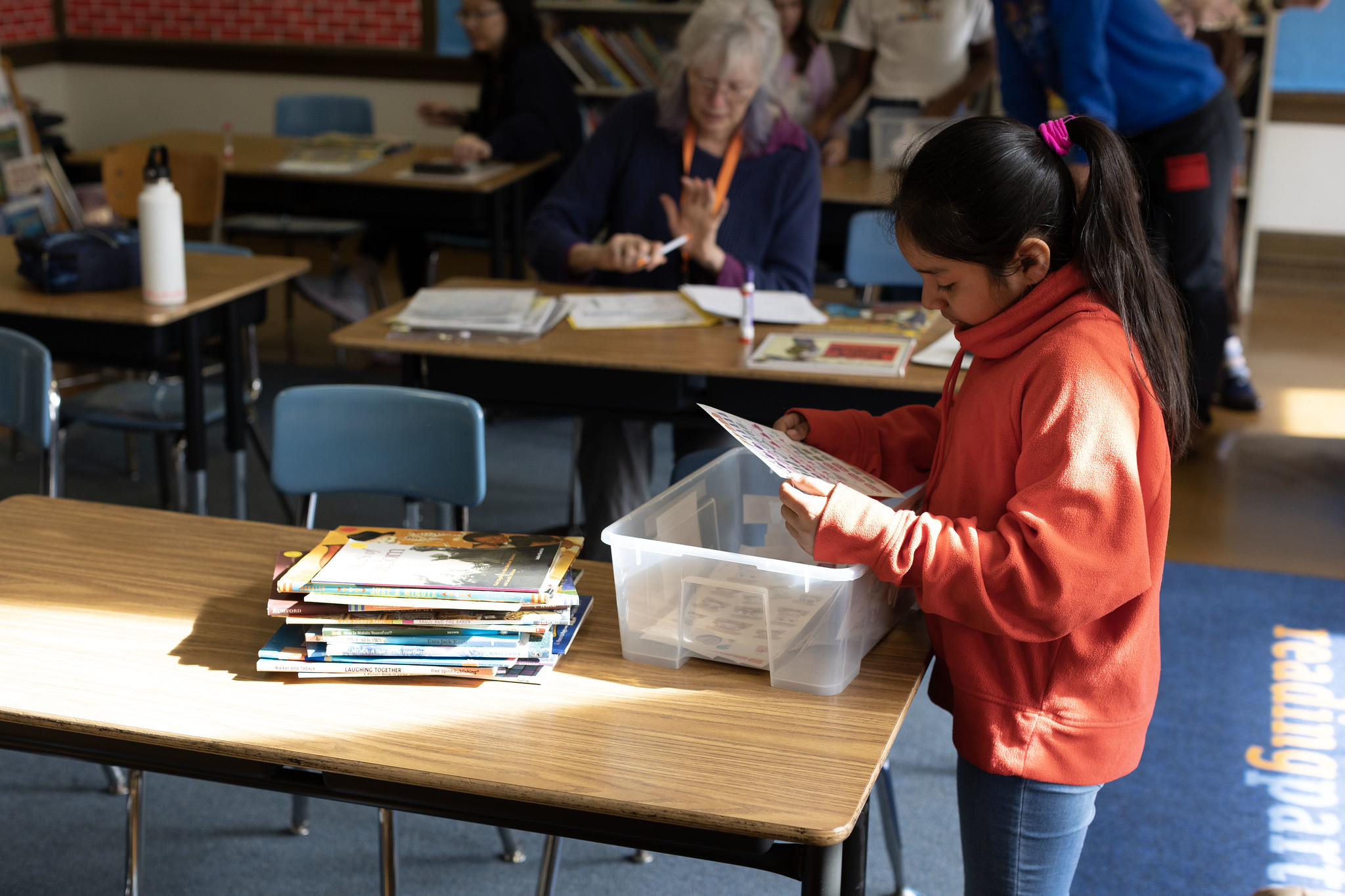 student choosing books from a box in a classroom, libraries