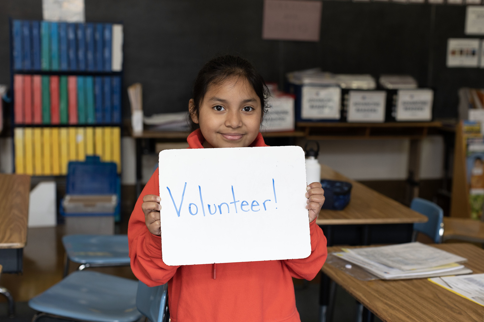 student holding up a sign saying "volunteer"