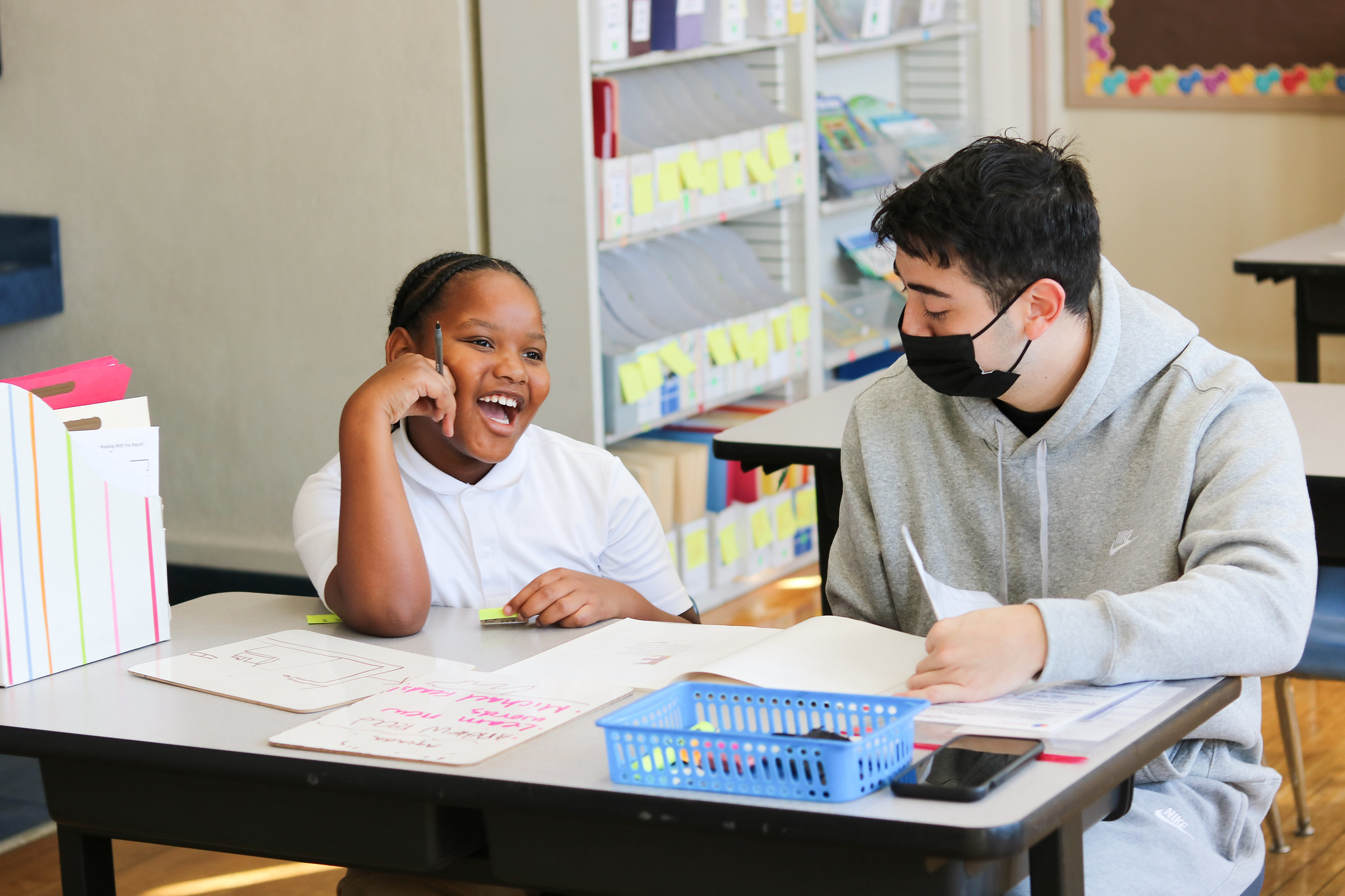 living longer through volunteering, a tutor and student work on literacy skills at a desk in a classroom