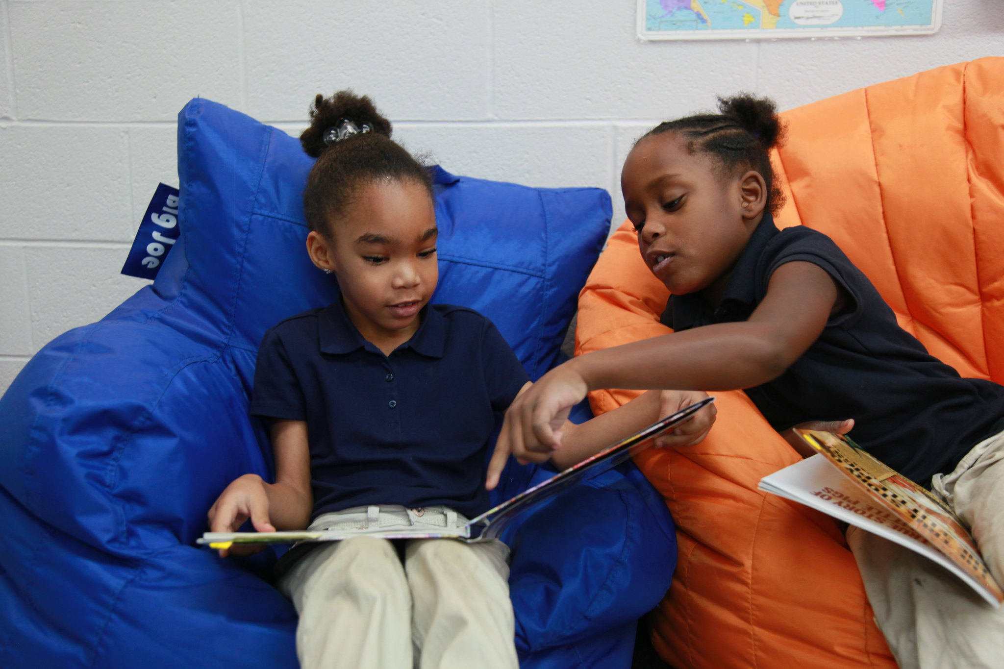 two students reading together on bean bag chairs