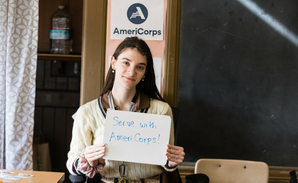 Member holding serve with AmeriCorps sign