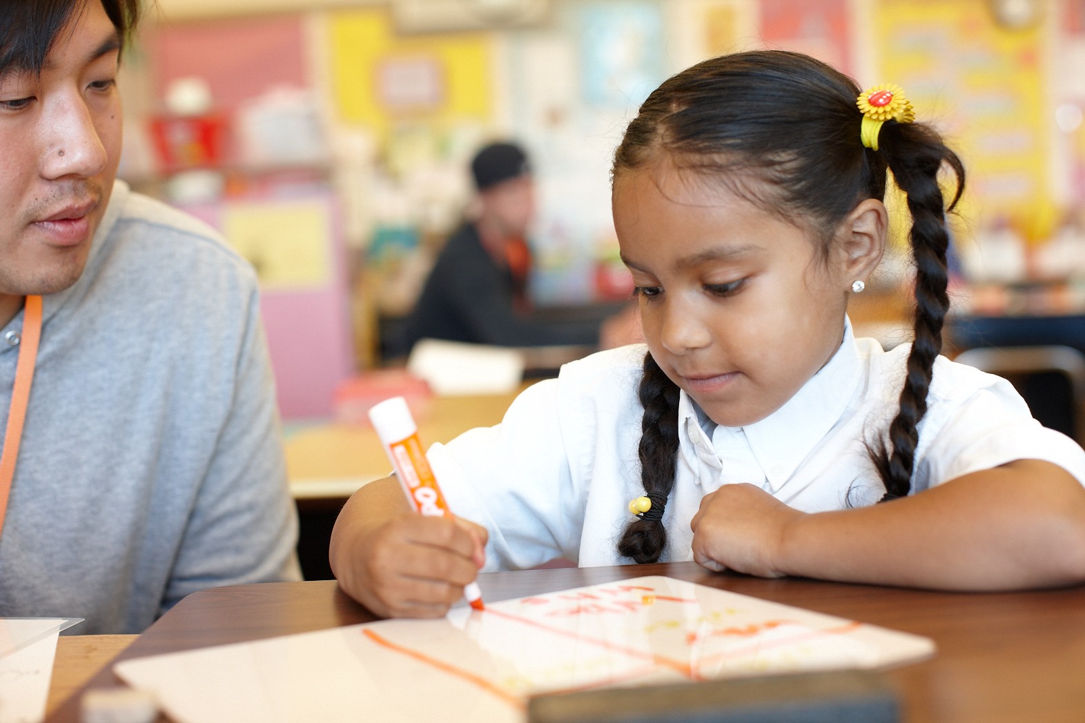 a young female students writes something with an orange marker on a dry-erase board, high-quality pre-k