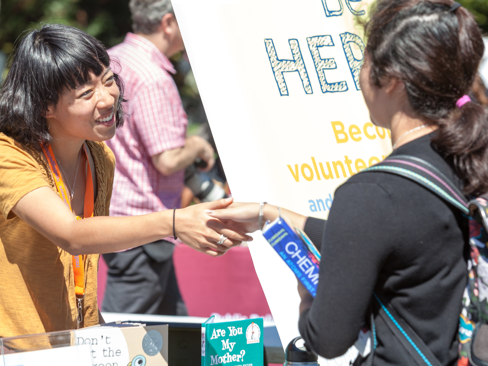 an americorps member at a table event shaking the hand of a community member