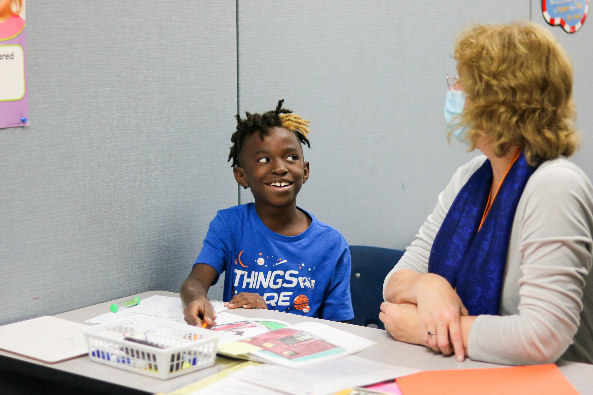 a tutor-student pair sit at a table with books open in front of them