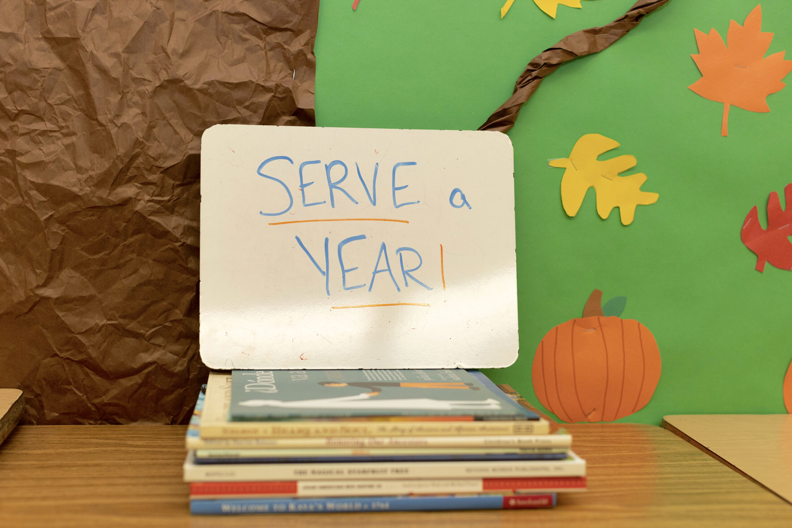 a whiteboard propped up on a stack of books that reads "serve a year," americorps gap year