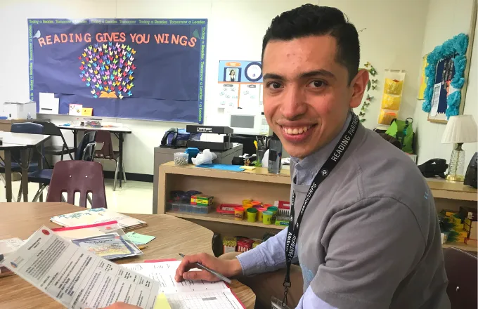 americorps member reviewing curriculum and student notes while smiling at camera