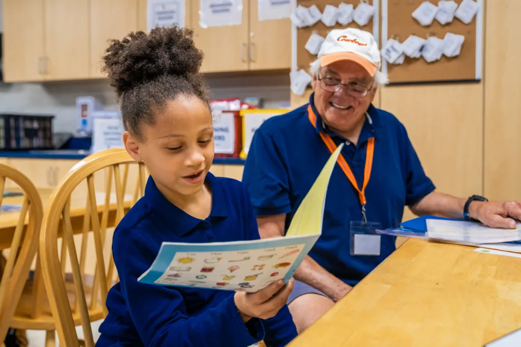 a student reading a book while their tutor looks at them proudly because reading is a civil right