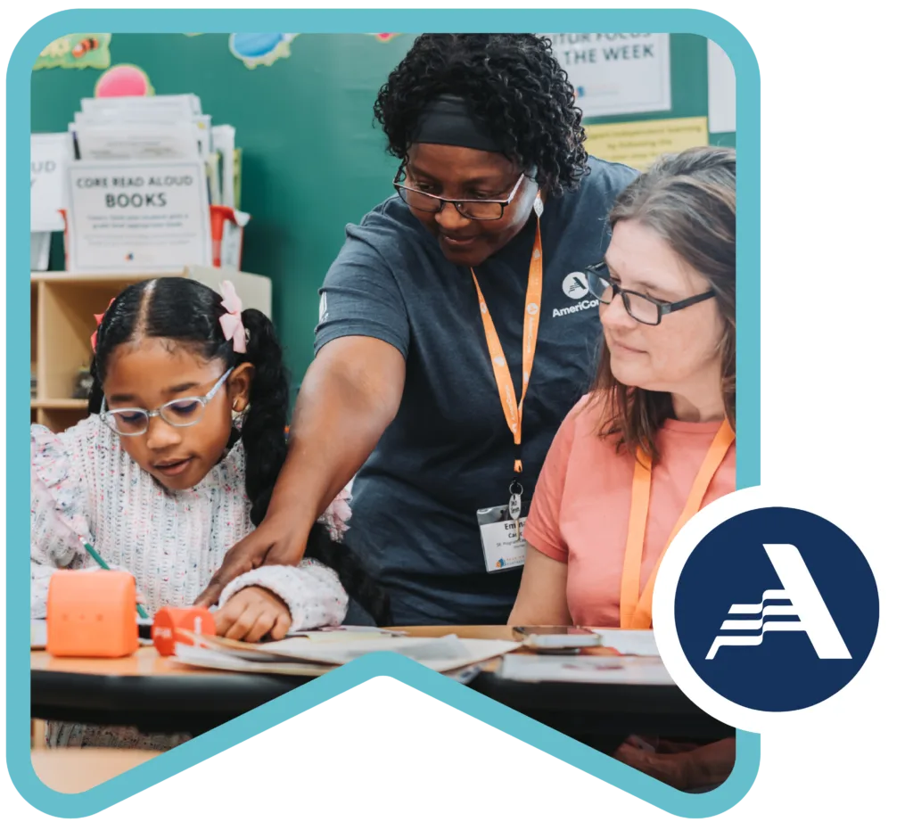 an americorps member pointing to a part of the literacy lesson that a tutor and student are working on