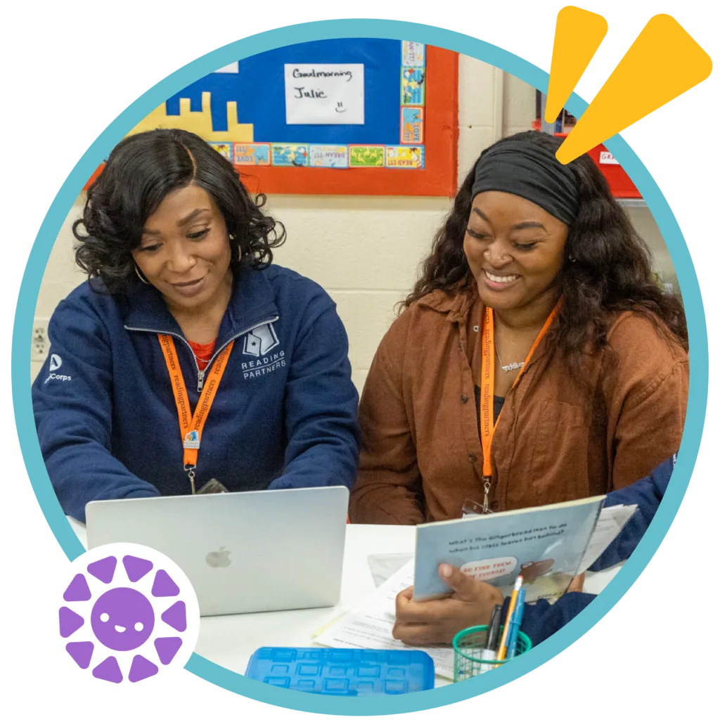 two members of the reading partners team using a computer and wearing the iconic orange lanyards