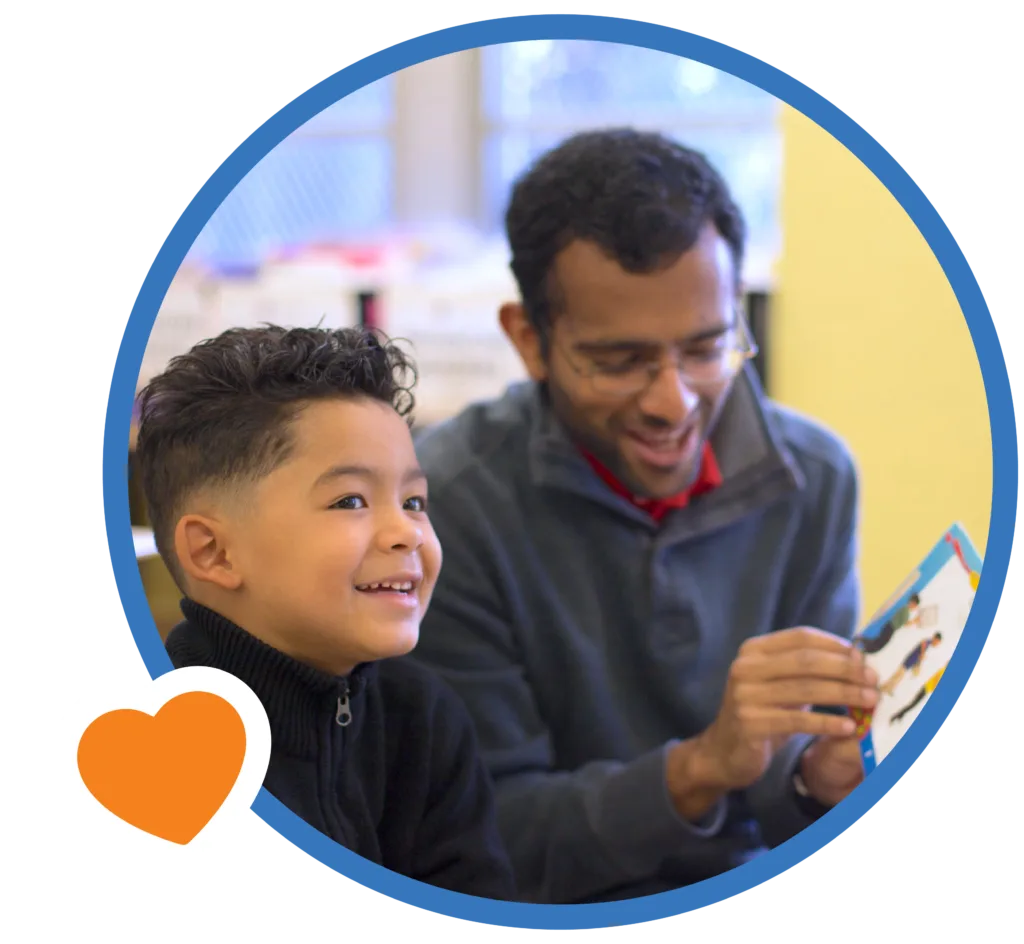 student-tutor pair during a literacy lesson, the tutor reading to the student and the student smiling