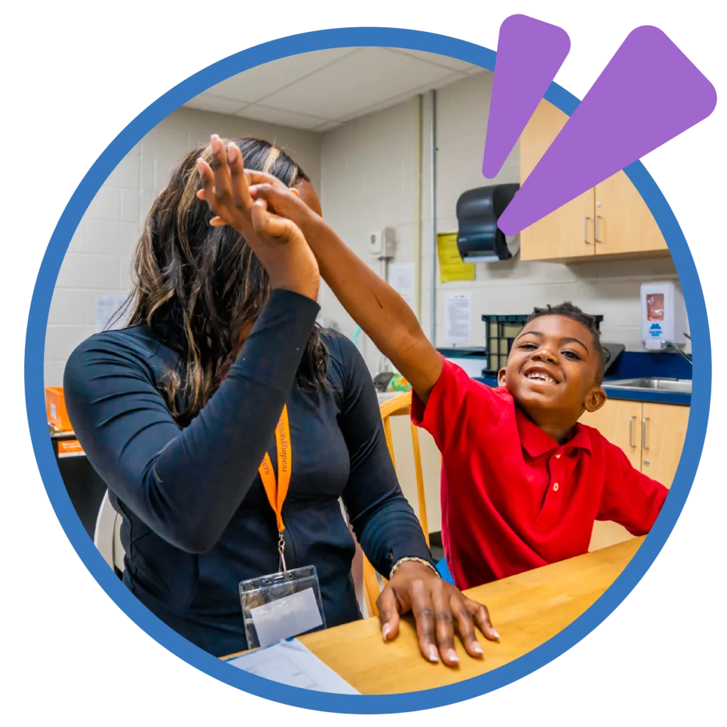 student high-fiving his tutor at a desk
