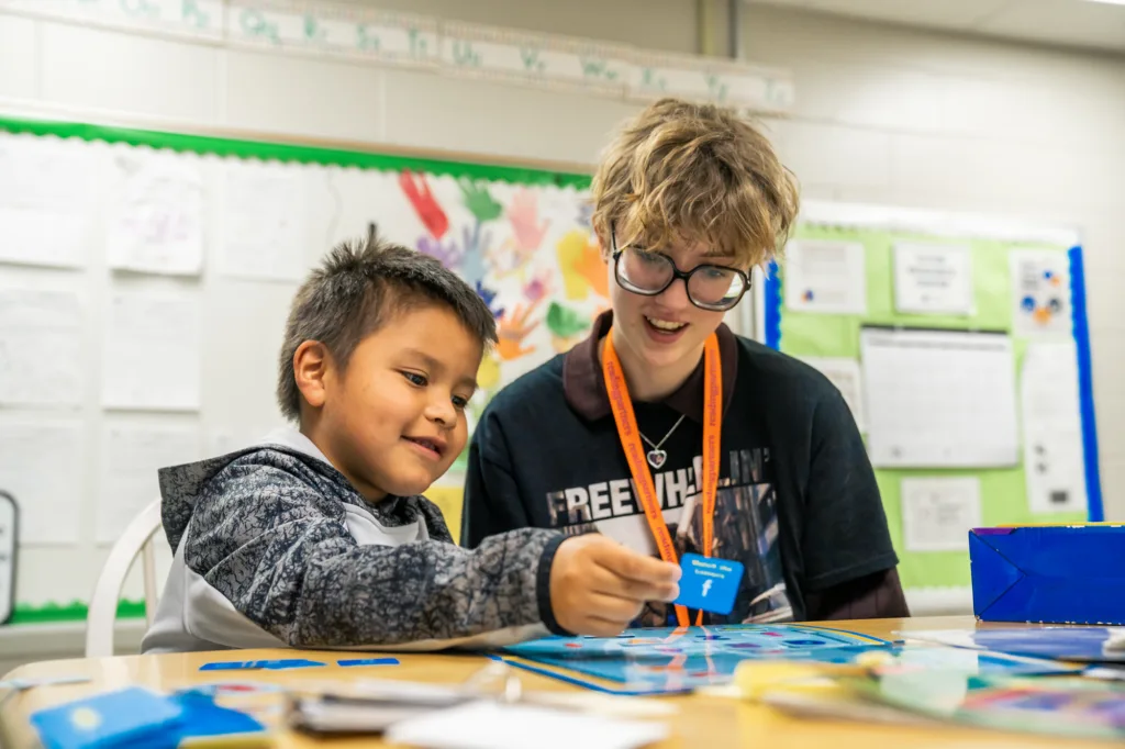 a student and tutor working on literacy skill-building activities in a classroom