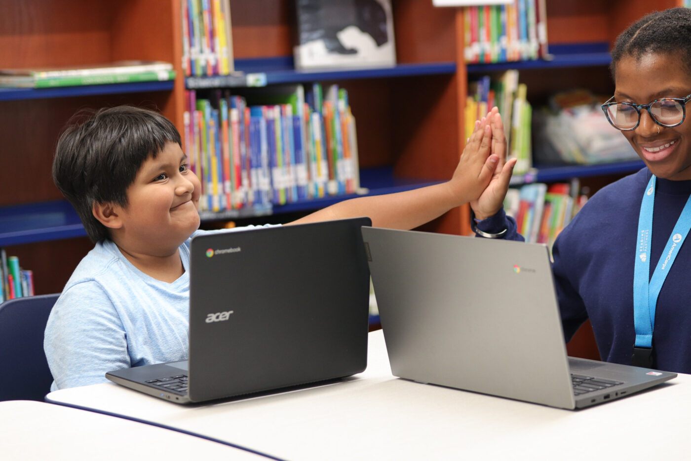 a student high-fiving an americorps member as he boosts his literacy skills using reading partners connects; programming in colorado and silicon valley