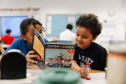 two students reading a cover to cover book during a reading partners tutoring session