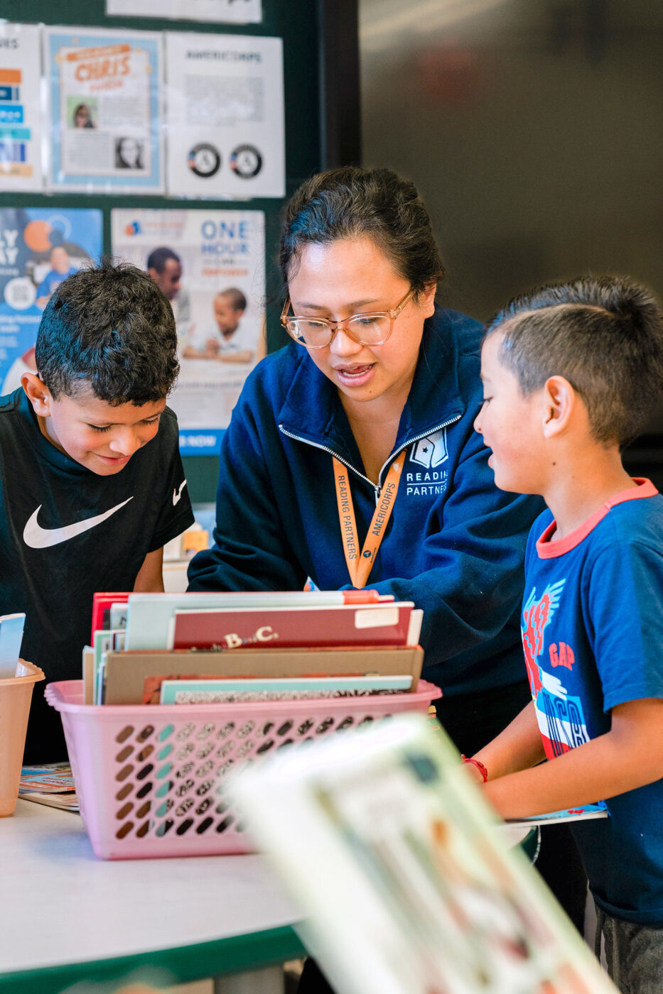 an americorps member and two students choosing books to take home