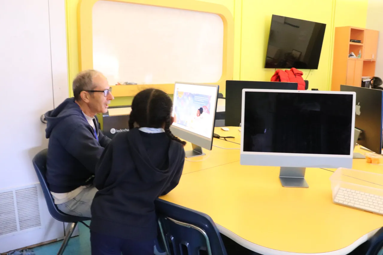 Free Virtual Tutoring in newark; a student and tutor sit at a computer while the student boosts their literacy skills